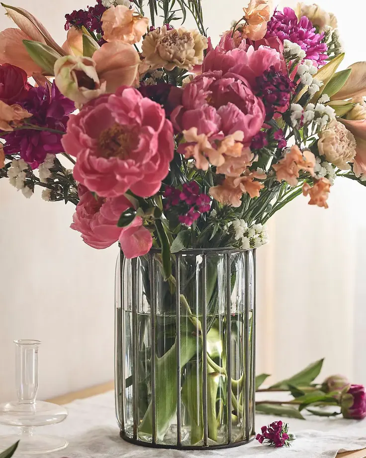 دسته گل رنگی در گلدان شیشه‌ای خط‌دار