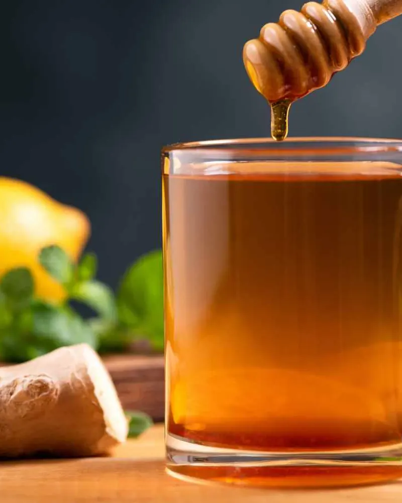 افزودن عسل به دمنوش لیمو با قاشق چوبی