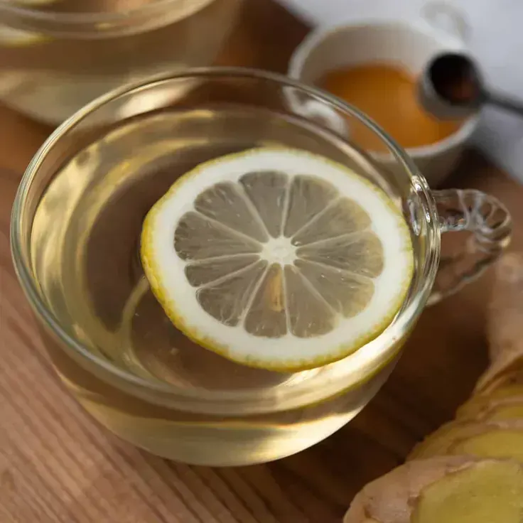 نوشیدنی لیمو و عسل در لیوان شیشهای روی میز چوبی
