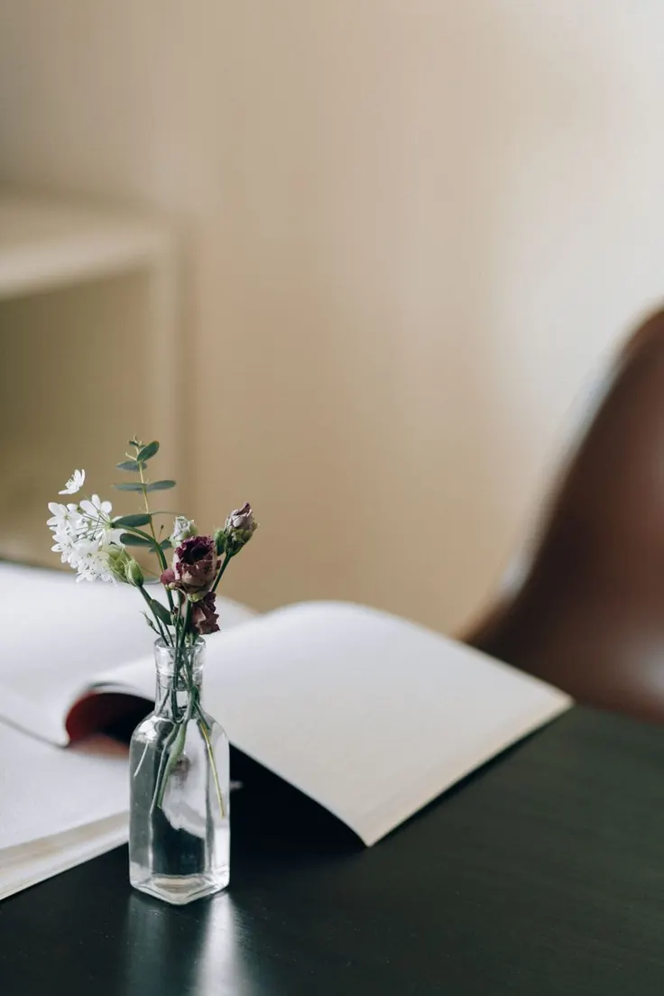 گلدان کوچک شیشه‌ای کنار کتاب
